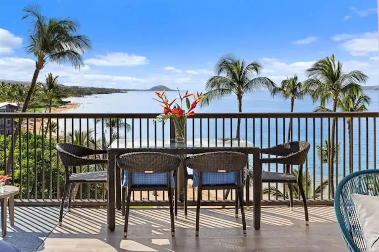 This lanai with garden furniture, fresh red flowers and ocean views belongs to one of the best condo rentals in Kihei Maui